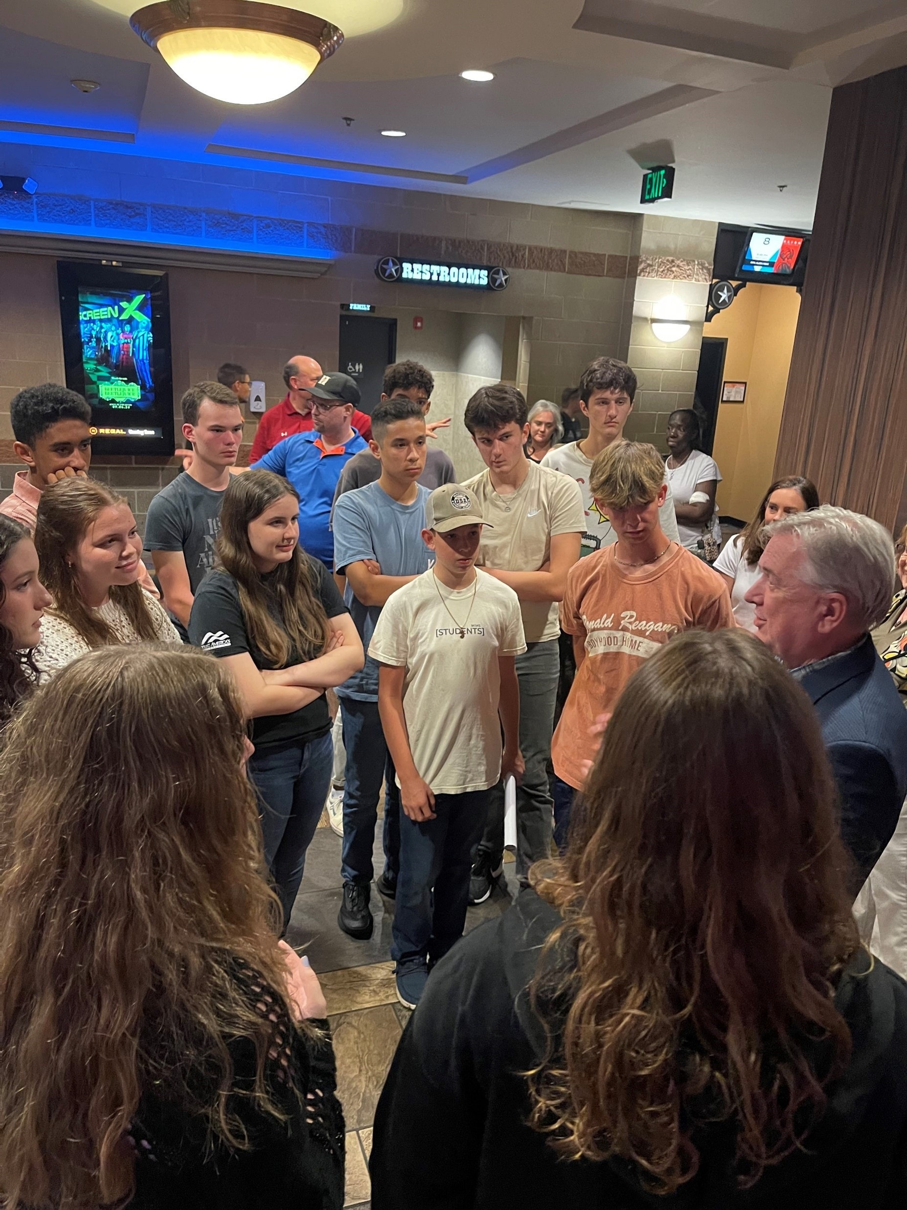 YAF Houston students gathered around a speaker at a movie theater lobby