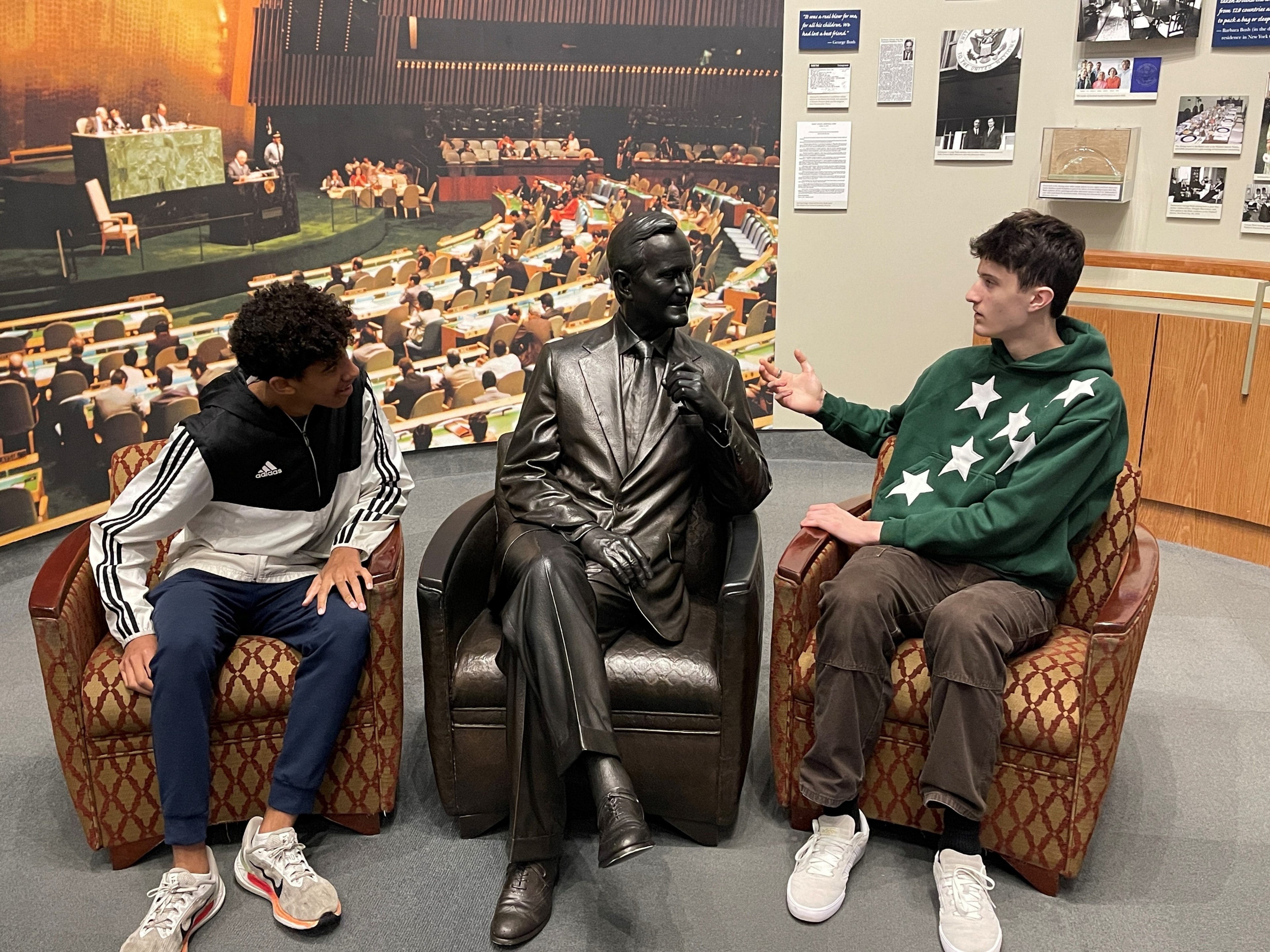 Two YAF Houston students posing with a George H.W. Bush statue at a presidential library